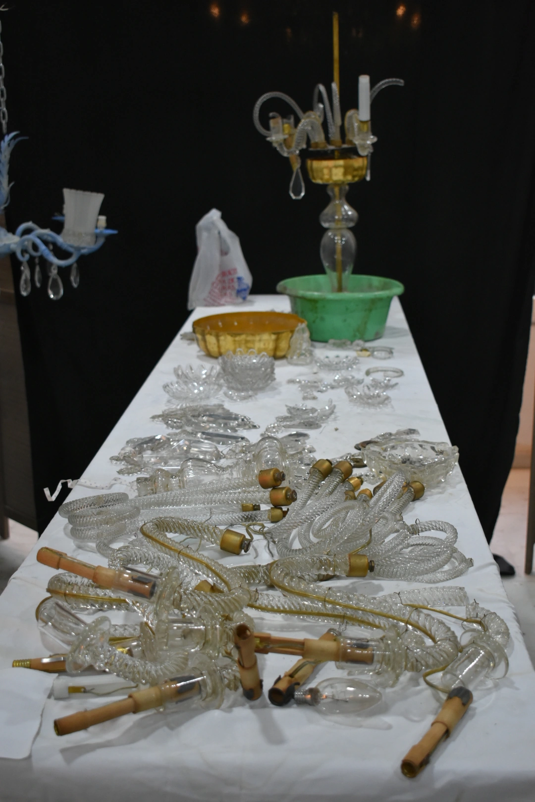 Lámpara de cristal desmontada sobre una mesa del taller antes de su restauración.